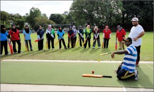 Aminul Islam, kneeling, directs coaching activity in Bander Seri Begawan, Brunei